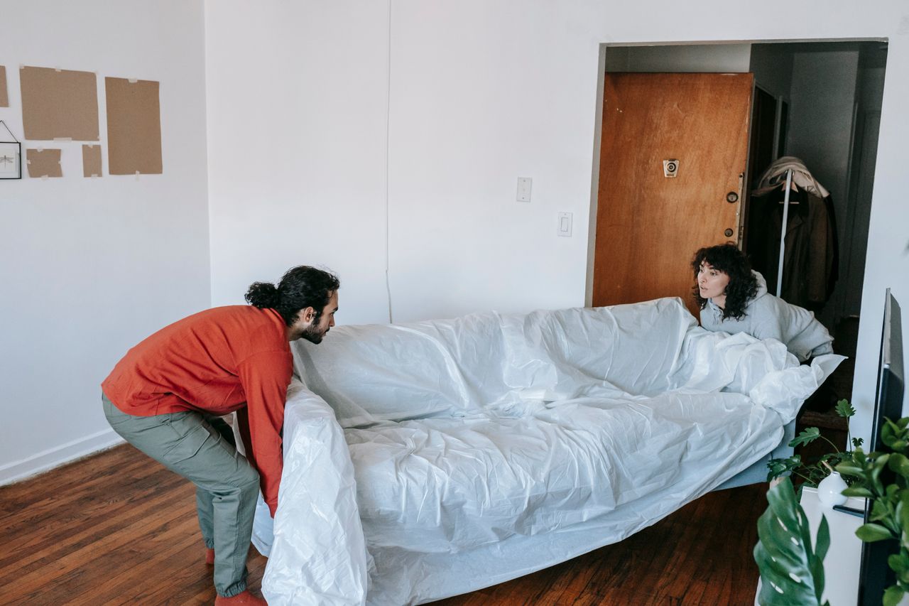 creative A couple collaboratively lifting a couch while moving into a new apartment.